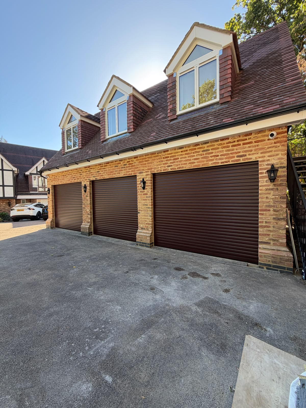 Close daytime view of the Totteridge garage conversion showing the three garage doors and dormer loft