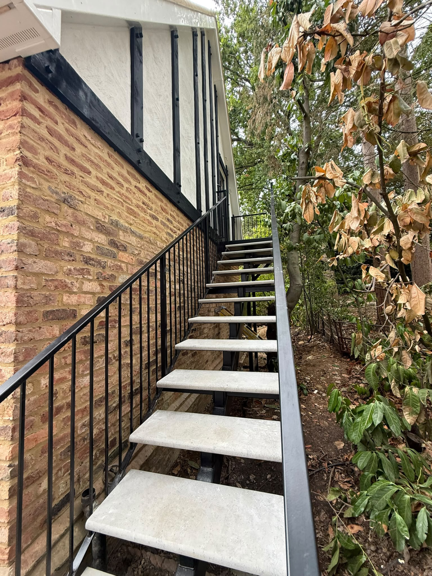 Bespoke garage conversion in Totteridge North London - The Construction Collective - bespoke external staircase with stone treads and black steel railings