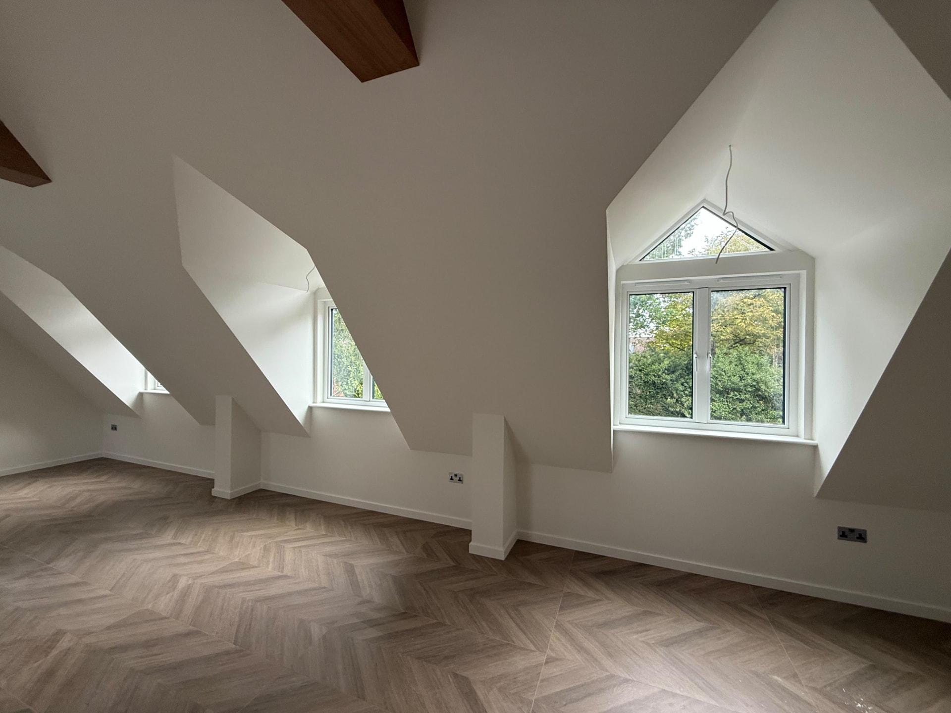 Bespoke garage conversion in Totteridge North London - The Construction Collective - completed upper-level living space with dormer windows and chevron flooring