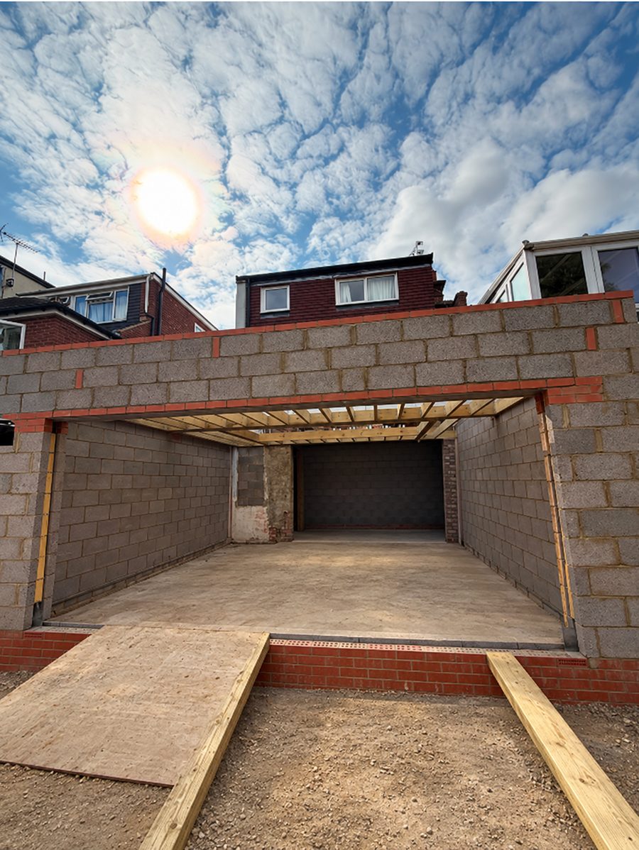 Blockwork shell of a single-storey rear extension in Barnet EN4, with a wide structural opening and timber roof joists framed around a central aperture for a roof lantern.