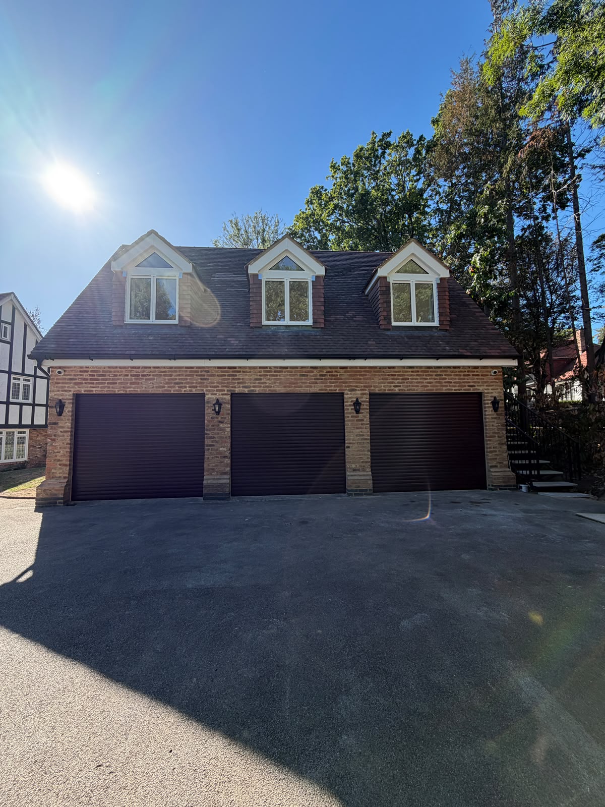 Daytime front elevation of the Totteridge garage conversion with three garage doors and three dormer windows