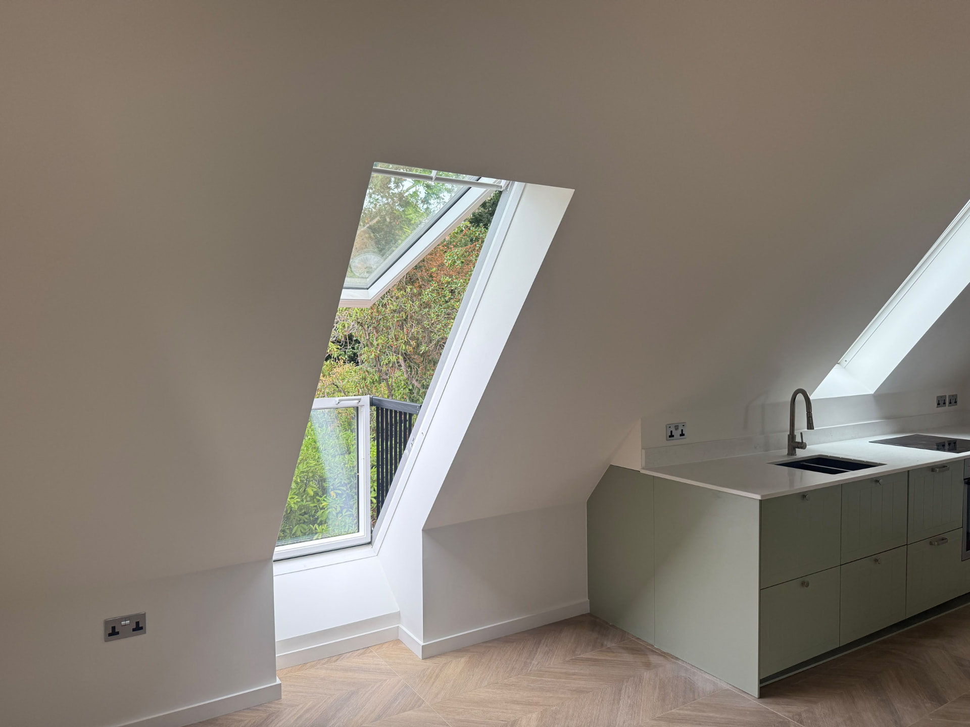 Bespoke garage conversion in Totteridge North London - The Construction Collective - fitted kitchen beneath sloping roofline with rooflight
